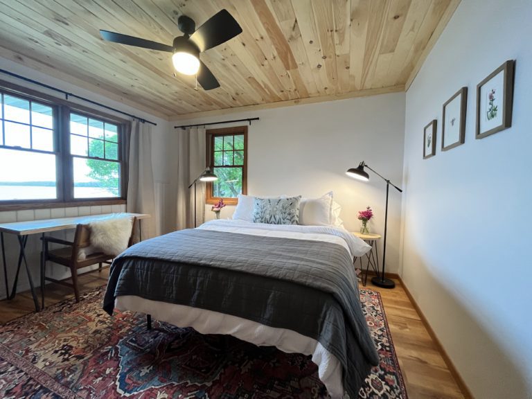 Lakeside bedroom with queen bed and work desk with lake view